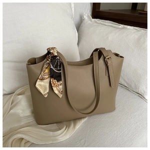 Detail of khaki tote bag handle wrapped with elegant vintage patterned silk scarf