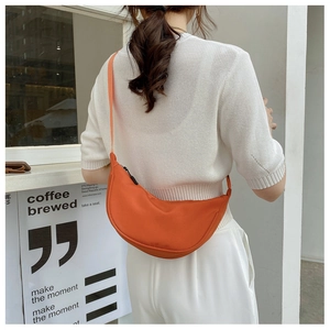 Detail of bright orange nylon half-moon crossbody bag with wide adjustable strap