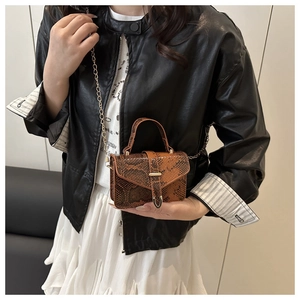 Detail view of mini brown snakeskin pattern handbag with metal chain strap on model