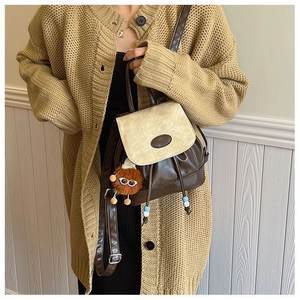 Detail van een vintage mini-rugzak in bruin en beige PU-leer met een pluche hanger