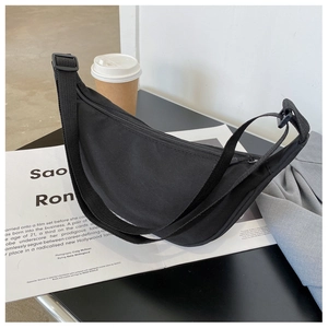 Flat lay of a black nylon crescent bag on a magazine next to a white coffee cup