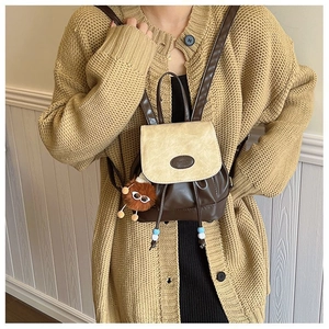 Mini brown and beige dual-tone backpack with FASHION emboss and plush monster charm