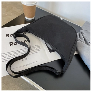 Detail of a black nylon crescent bag with adjustable strap in a casual lifestyle setting