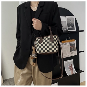 Detail of checkered handbag with brown leather trim and cute rabbit pendant charm