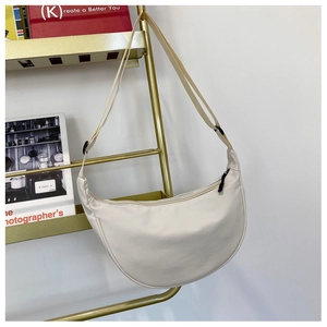 Macro detail of cream nylon crescent bag showing fine texture and adjustable strap