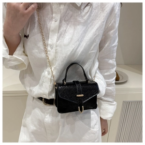 Detail of black faux snakeskin mini bag with gold chain strap and buckle on white outfit