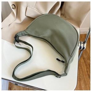 Macro view of army green nylon crescent bag with adjustable strap on white chair