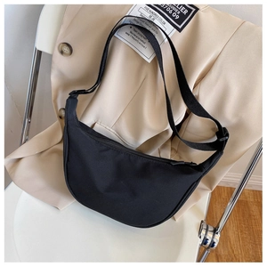 Side view of black nylon crescent bag featuring adjustable fabric strap and zipper closure