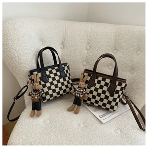 Detail of checkered canvas handbags with leather trim and cute rabbit doll charms
