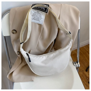 Detailed view of a white nylon crescent bag with adjustable strap and black zipper accent