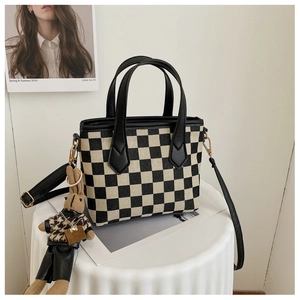 Detail of checkered tote bag with golden hardware and cute bunny pendant charm