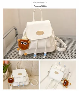 Detail van een crèmewitte mini-rugzak met pluchen hanger en trekkoord met kralen