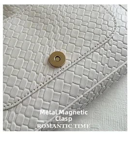 Close-up of white woven shoulder bag featuring a premium gold magnetic clasp and texture