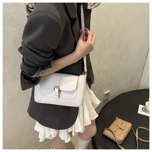 Detail of woven texture flap bag with polished gold metallic pin buckle and long strap