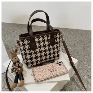 Detail of houndstooth plaid mini tote with brown leather handles and a cute rabbit charm