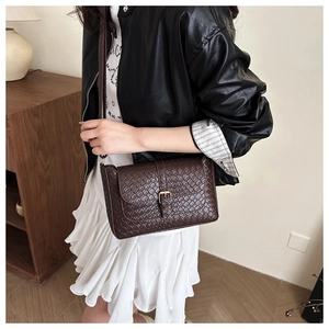 Detailed close-up of dark brown woven texture shoulder bag with gold buckle on model