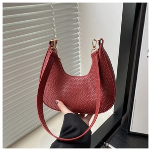 Détail de la texture tressée rouge et forme demi-lune du sac élégant sous le bras
