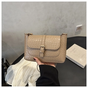 Detail of beige textured leather handbag featuring crocodile pattern and metal buckle