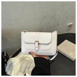 Detailed view of white crocodile pattern faux leather texture with golden metal clasp