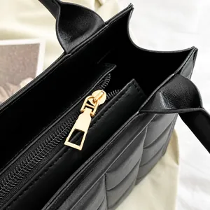 Detail of the high-quality gold zipper and quilted pattern on this black tote bag
