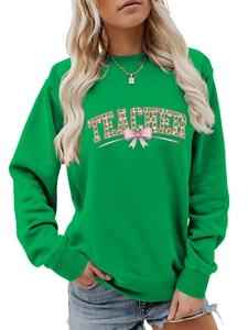 Close-up of emerald green sweatshirt with TEACHER text and clover bow graphic detail