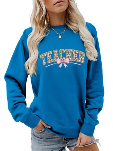 Close-up of Teacher lettering with clover pattern and pink bow on blue sweatshirt