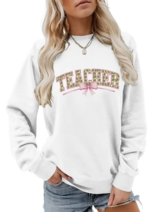 Close-up of Teacher lettering with green shamrocks and pink bows on a white sweatshirt