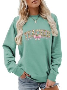 Detail of mint green sweatshirt with clover-filled TEACHER text and a pink bow