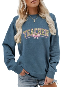Detail of navy sweatshirt featuring 'TEACHER' lettering with clover print and a pink bow