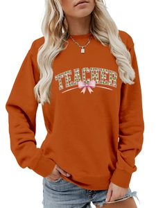 Detail of orange sweatshirt with TEACHER print, clover pattern and pink bow decoration