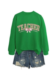 Detailed view of teacher sweatshirt with shamrock and bow print on green fabric