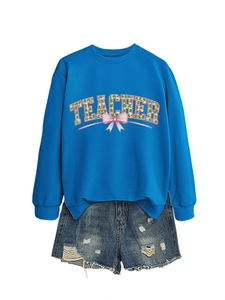 Detail of bright blue teacher sweatshirt with clover pattern and pink bow graphics