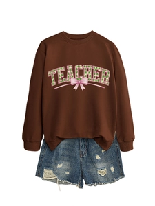Detail of Teacher sweatshirt with green shamrock pattern and pink bow on brown fabric