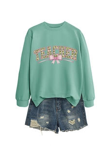 Detail of mint green Teacher sweatshirt with clover pattern and pink bow design