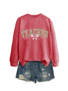 Detail of dark red sweatshirt with TEACHER text and shamrock pattern and denim shorts