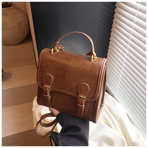 Detail view of the vintage brown faux leather bag with metal buckle strap and top handle