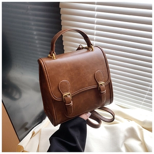 Detailed close-up of brown PU leather bag featuring gold buckles and a top handle