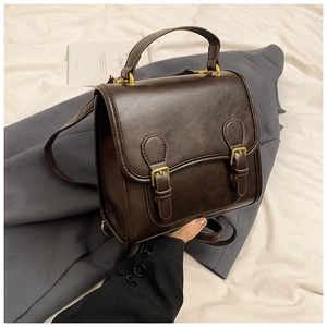 Detail of vintage brown PU leather handbag with gold buckles and adjustable shoulder strap