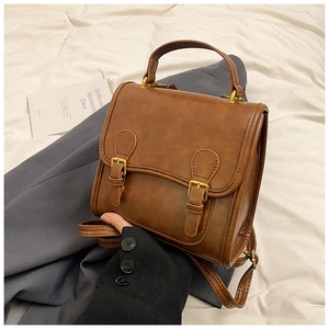 Close-up of vintage brown leather backpack with gold buckles and top handle detail