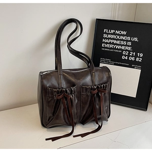 Close-up of chocolate brown faux leather tote with pleated pockets and ribbon bow detail