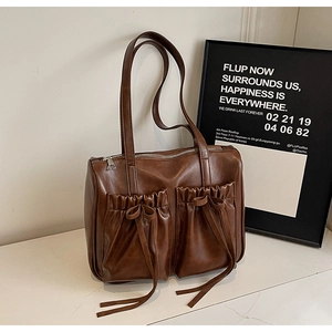 Detail of vintage brown leather tote bag with pleated double pockets and bow ties