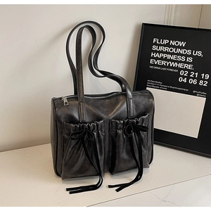 Detail of black PU tote bag with pleated pockets and delicate bow ribbon accents