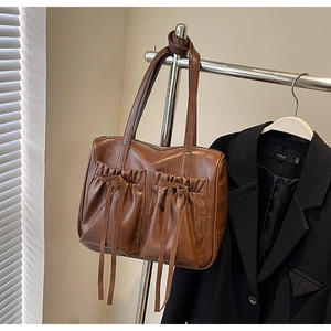 Detail of vintage brown leather tote bag with pleated pockets and decorative bows
