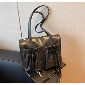 Close-up of vintage dark brown faux leather shoulder bag with bow ties and front pockets