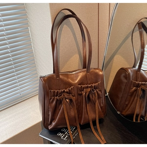 Detail of dark brown vintage faux leather shoulder bag with pleated drawstring pockets