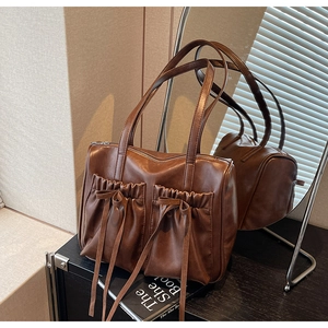 Detailed view of dark brown PU leather handbag with decorative bows and front pockets