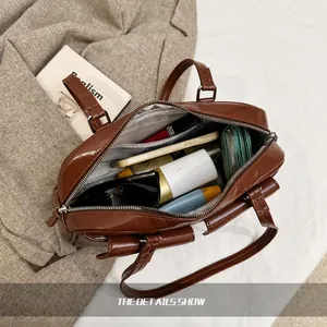Vista superior del interior espacioso del bolso marrón brillante con objetos diarios