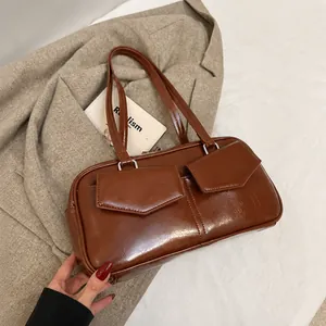 Detalle de bolso retro marrón con dos bolsillos de solapa y acabado en cuero sintético brillante