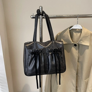 Retro black faux leather tote bag with bow accents and large pockets for commuting