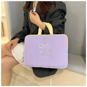 Detail of purple laptop bag featuring white embroidered bow and yellow handles